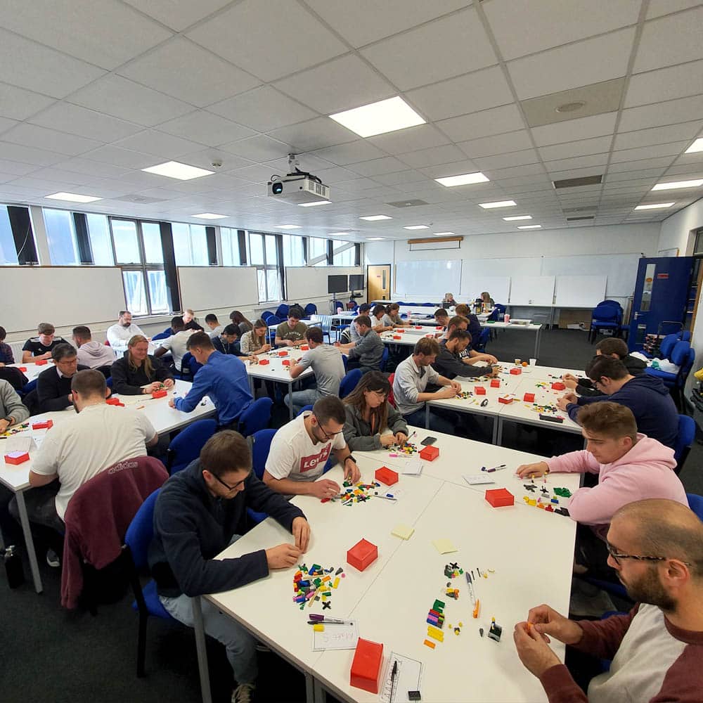 a room full of over 50 people nuilding LEGO models