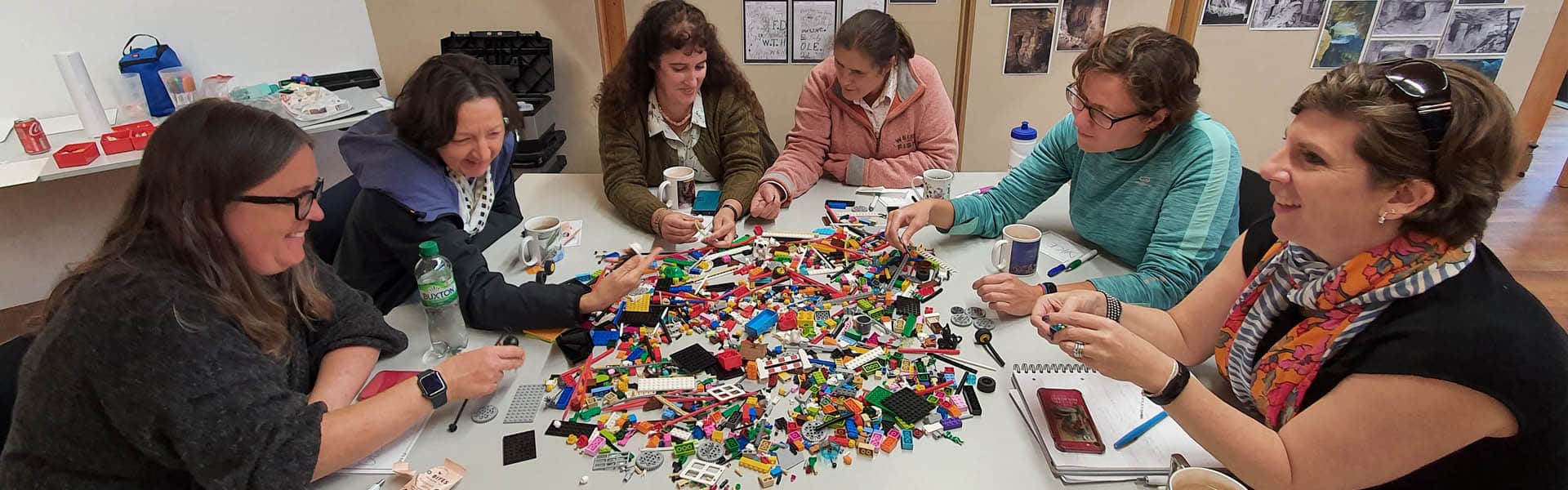 6 women sitting at a table using a huge pile of LEGO