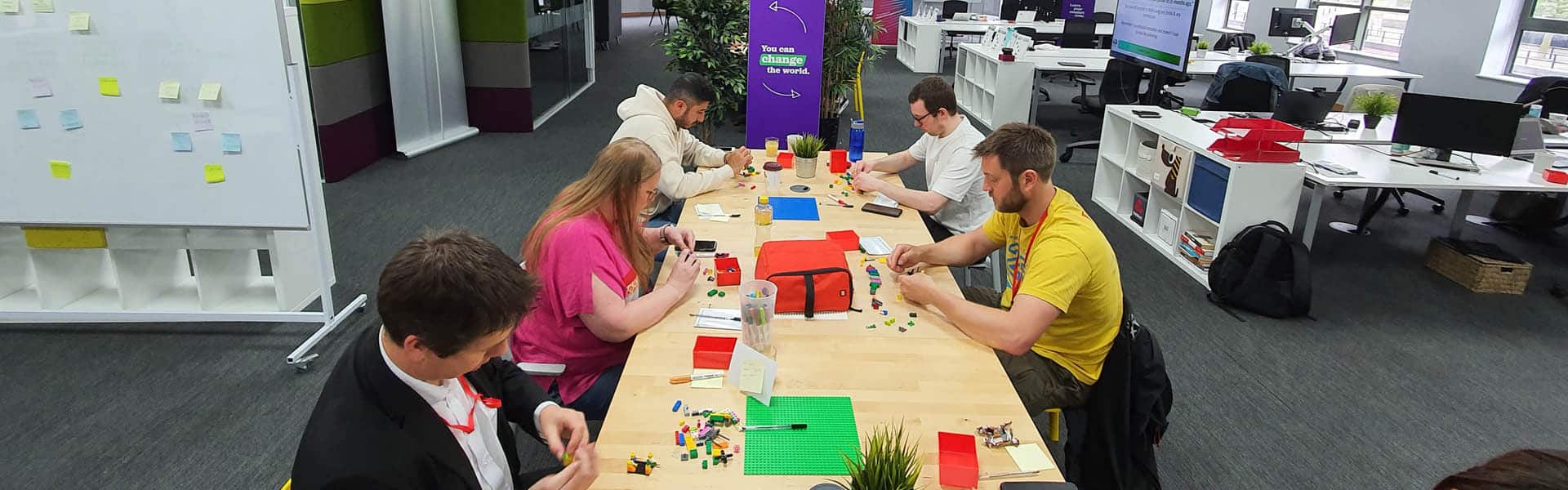 People surround a table as a facilitator shows a concept with Lego serious play